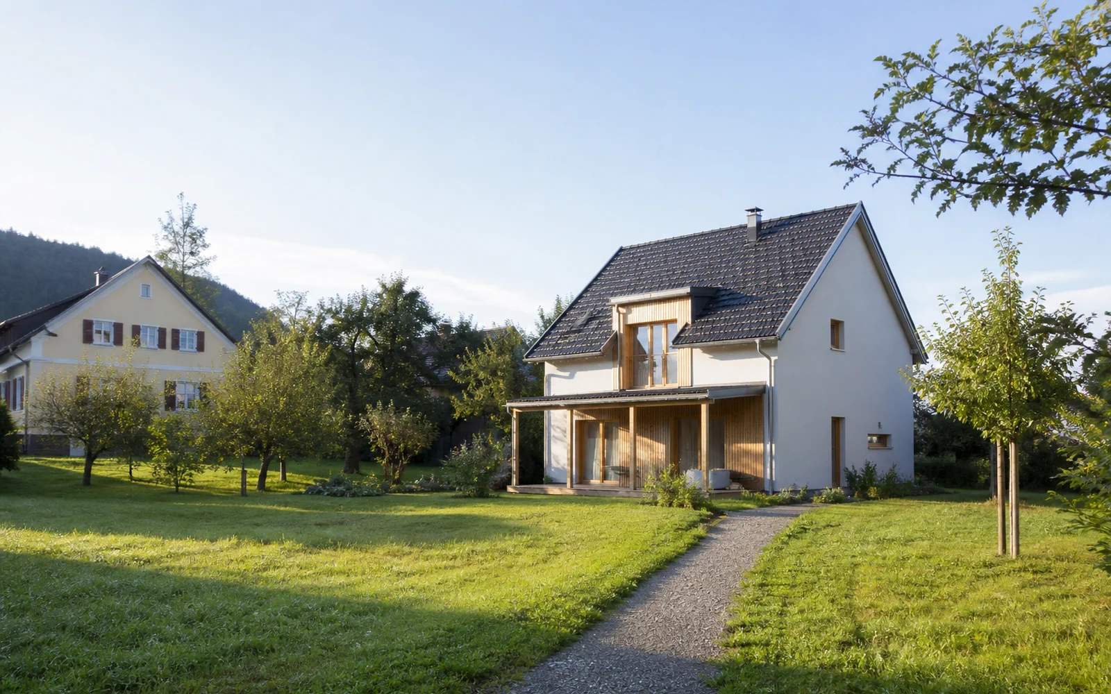 Freier gepflegter Platz mit Weg zu einem jüngeren und einem älteren Wohnhaus